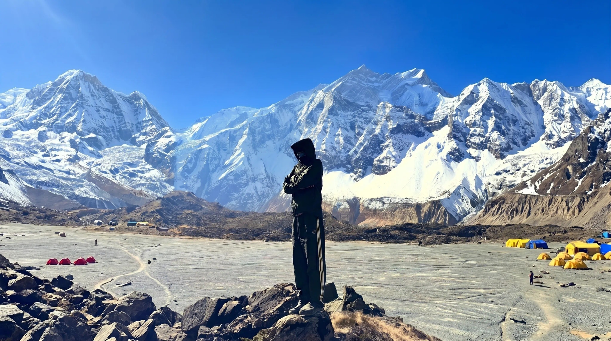 Mountaineer at high-altitude base camp with glacial peaks behind