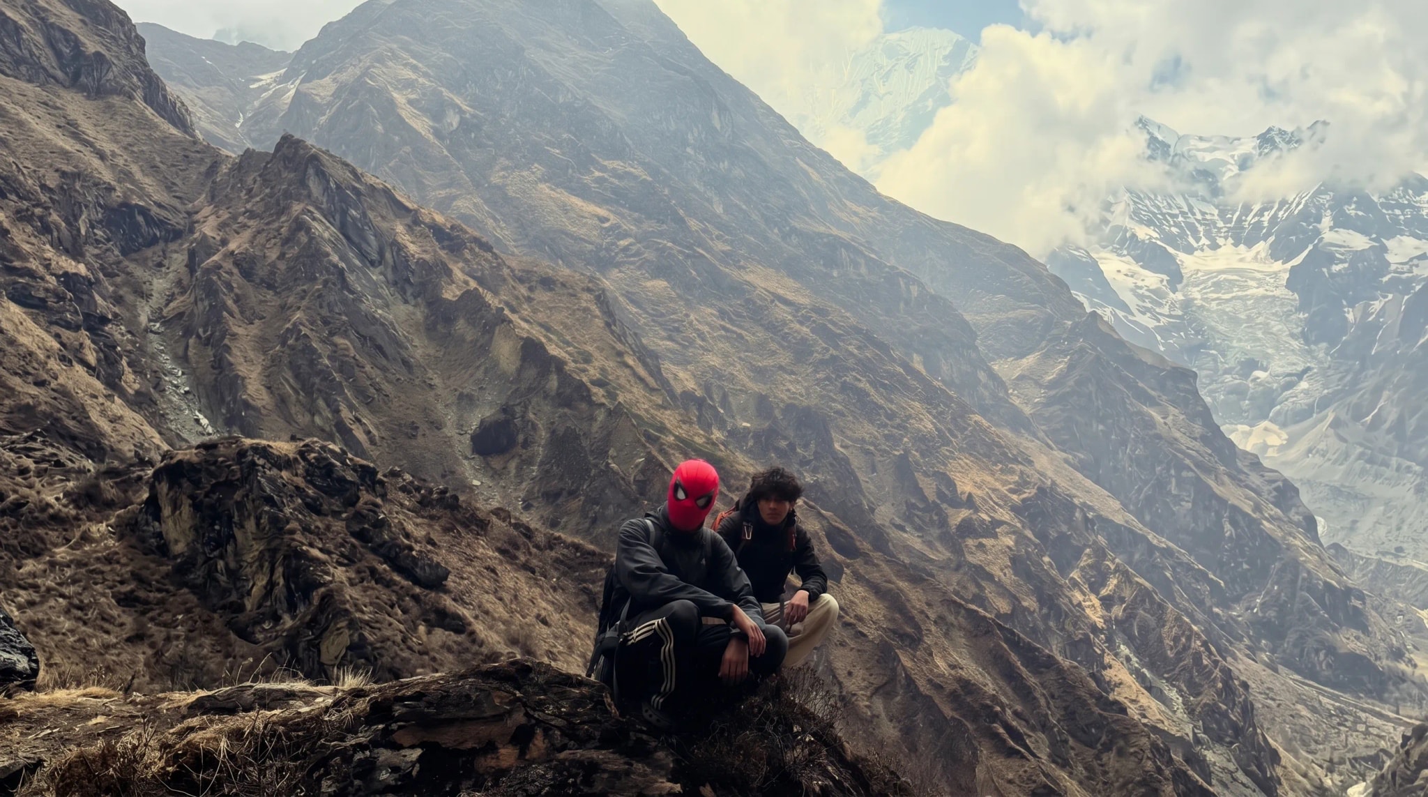 Two trekkers resting on rocky summit, glacier behind
